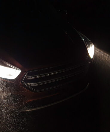 Headlights of the car shine at a heavy snowfall.